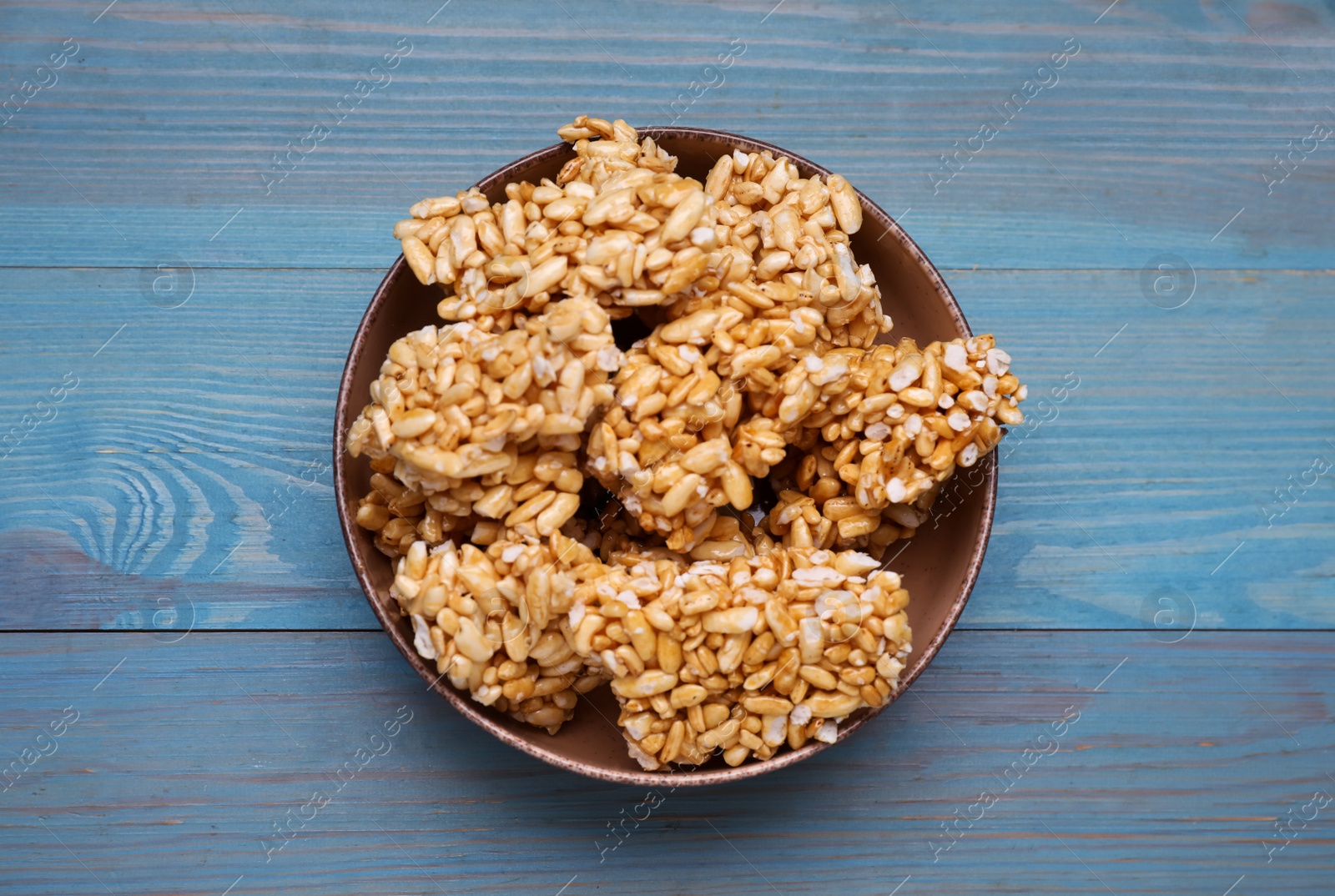 Photo of Bowl of puffed rice bars (kozinaki) on light blue wooden table, top view