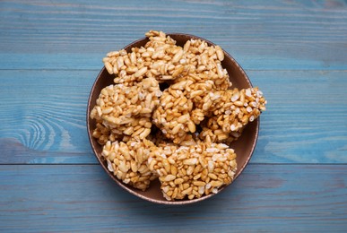 Bowl of puffed rice bars (kozinaki) on light blue wooden table, top view