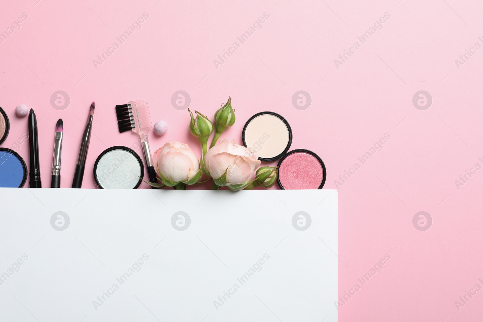 Photo of Flat lay composition with card and products for decorative makeup on pastel pink background