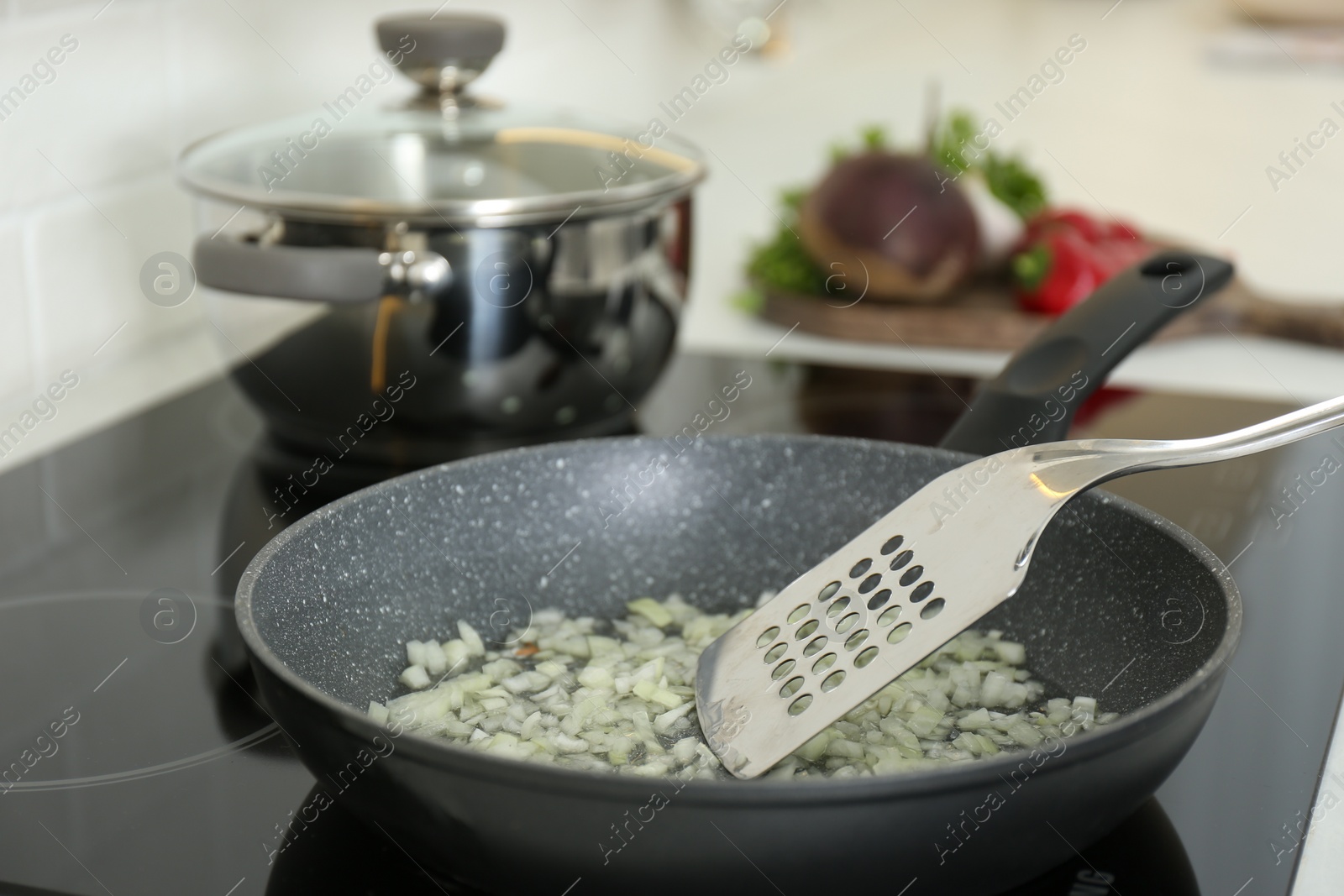 Photo of Frying chopped onion on cooktop in kitchen, closeup