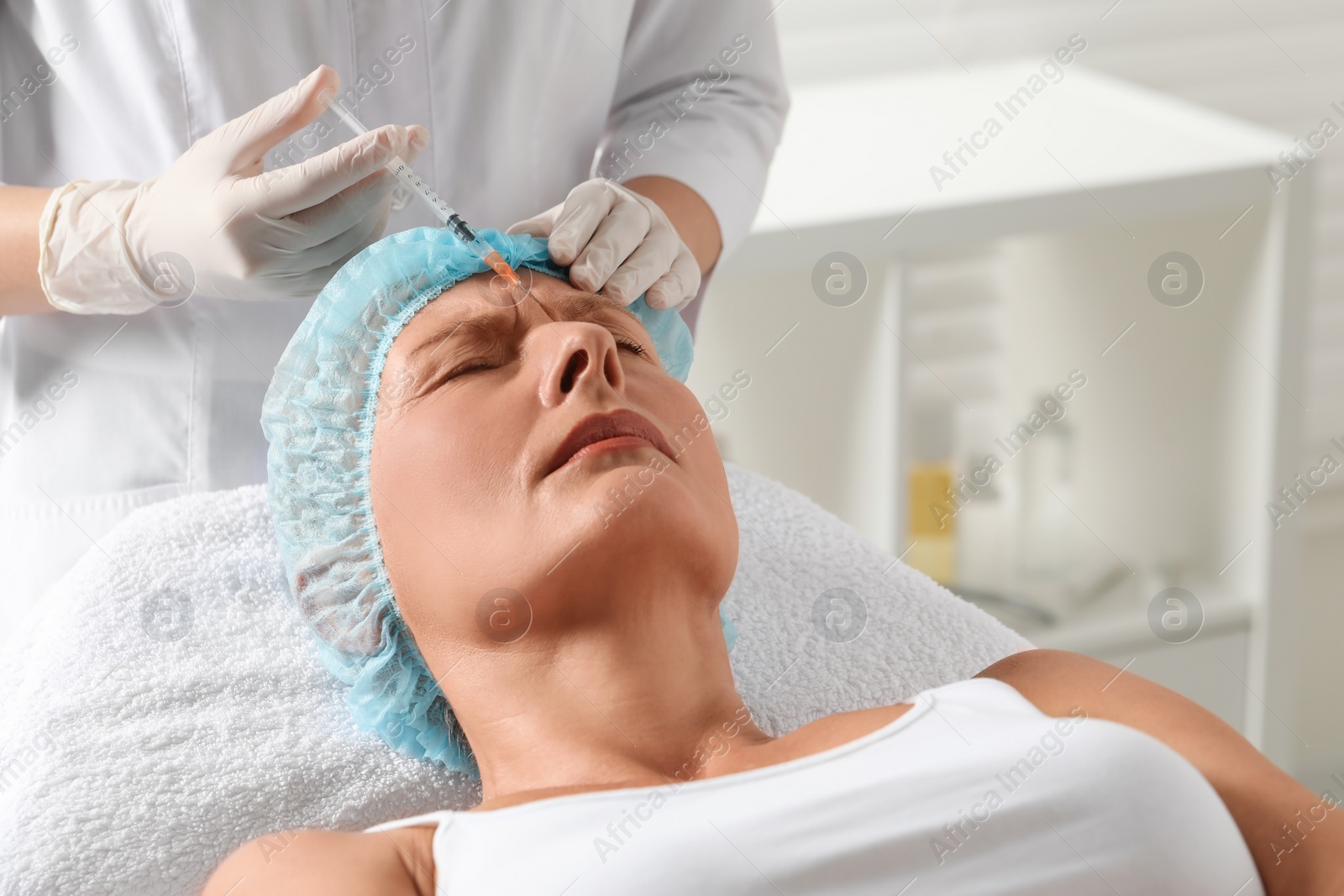 Photo of Doctor giving facial injection to senior woman in clinic. Cosmetic surgery