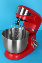 Photo of Modern red stand mixer on turquoise background