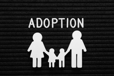 Family figure and word Adoption on black letter board, flat lay