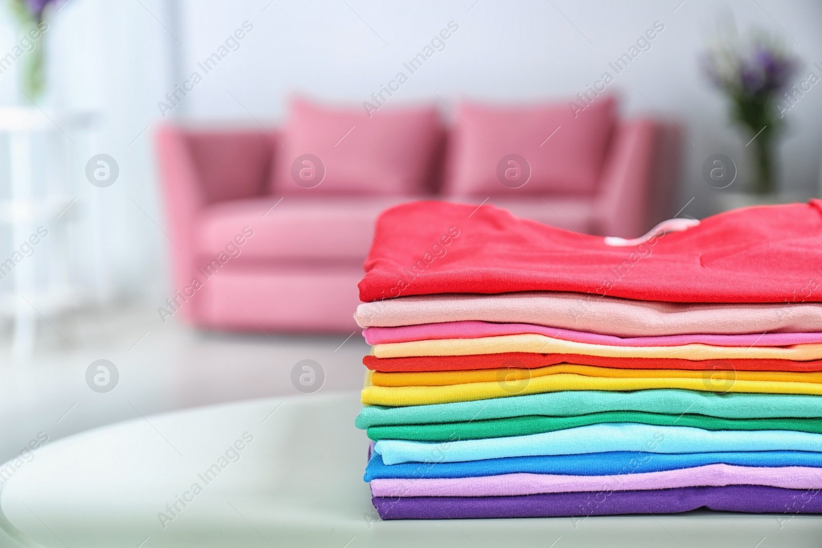 Photo of Stack of colorful t-shirts on table in living room