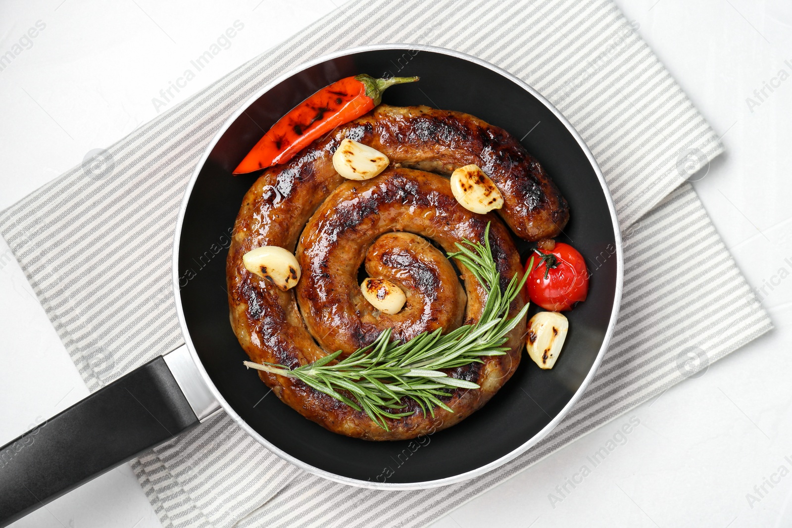 Photo of Delicious homemade sausage with garlic, tomato, rosemary and chili in frying pan on white table, top view