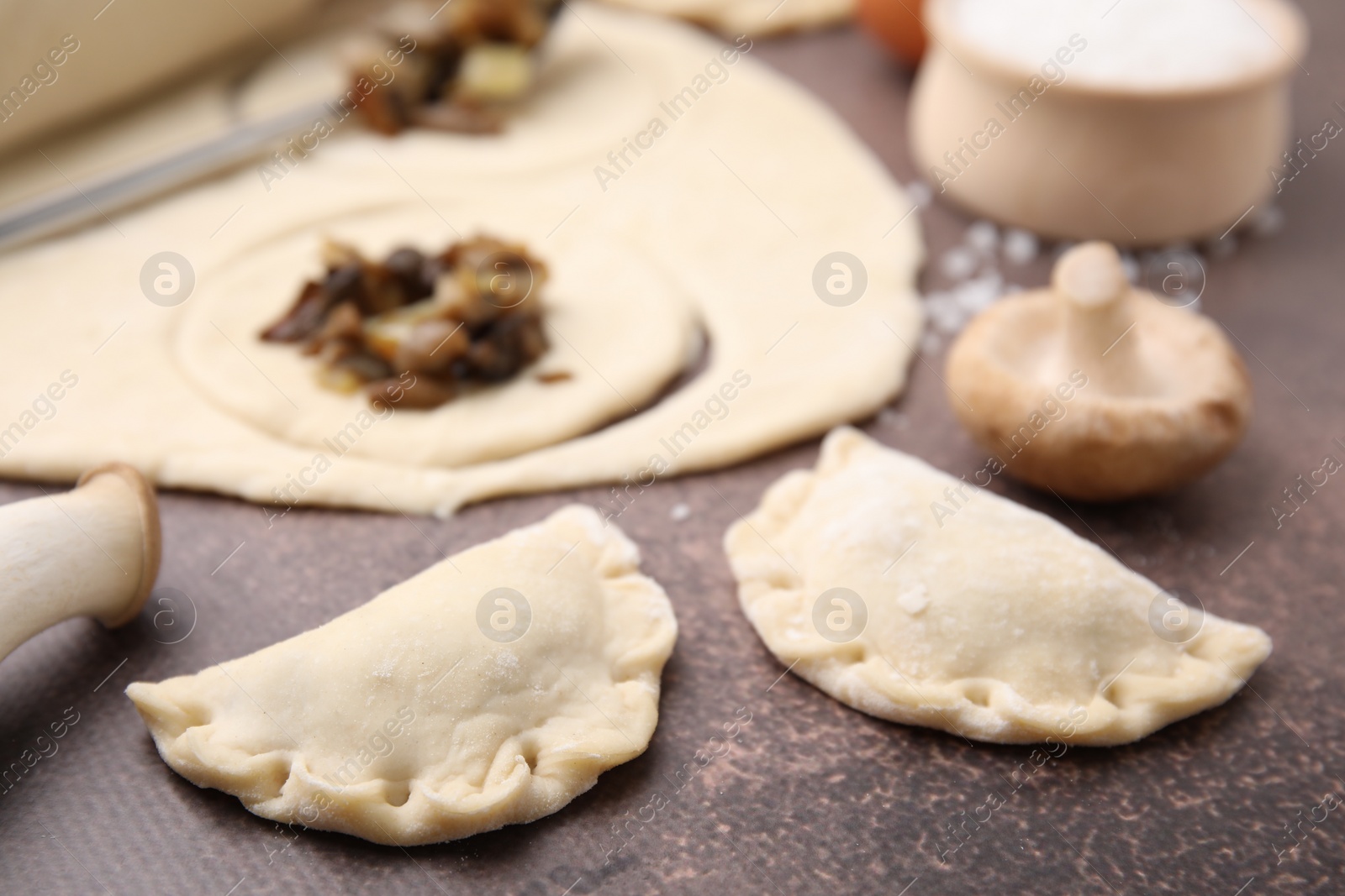 Photo of Process of making dumplings (varenyky) with mushrooms. Raw dough and ingredients on grey table, closeup