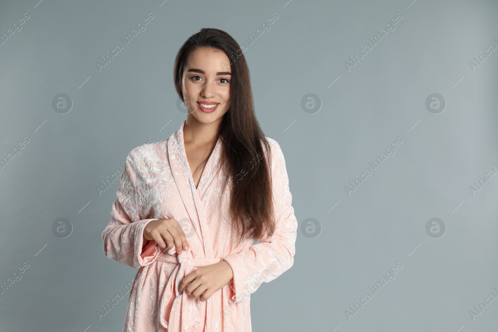 Photo of Beautiful young woman in bathrobe on grey background. Space for text