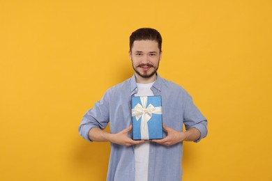 Photo of Happy man with gift on orange background