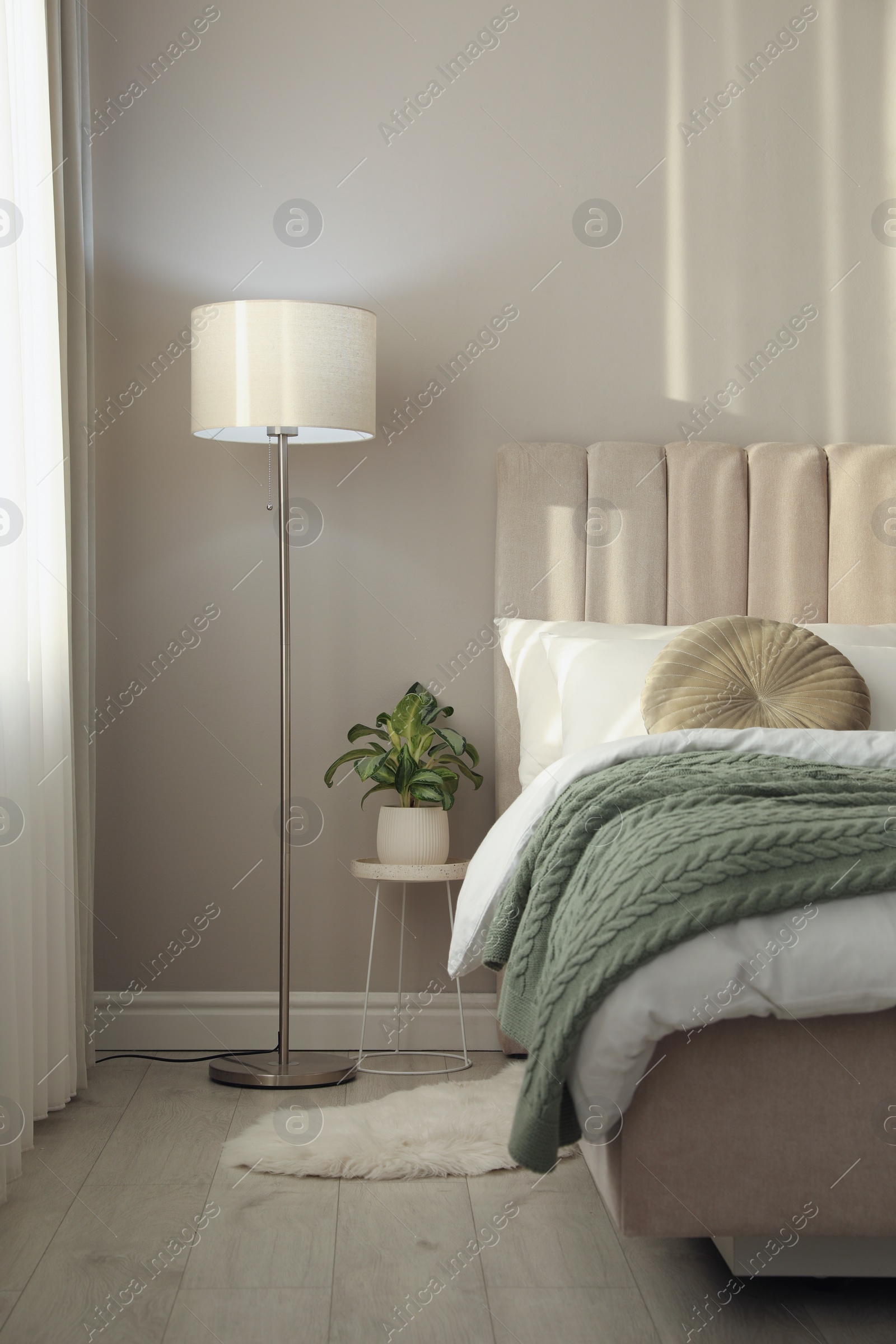 Photo of Stylish floor lamp and plant in bedroom. Interior element