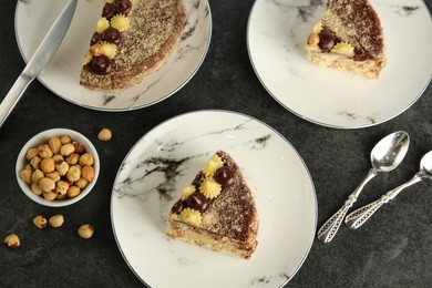 Photo of Delicious Kyiv Cake decorated with cream and hazelnuts served on black table, flat lay