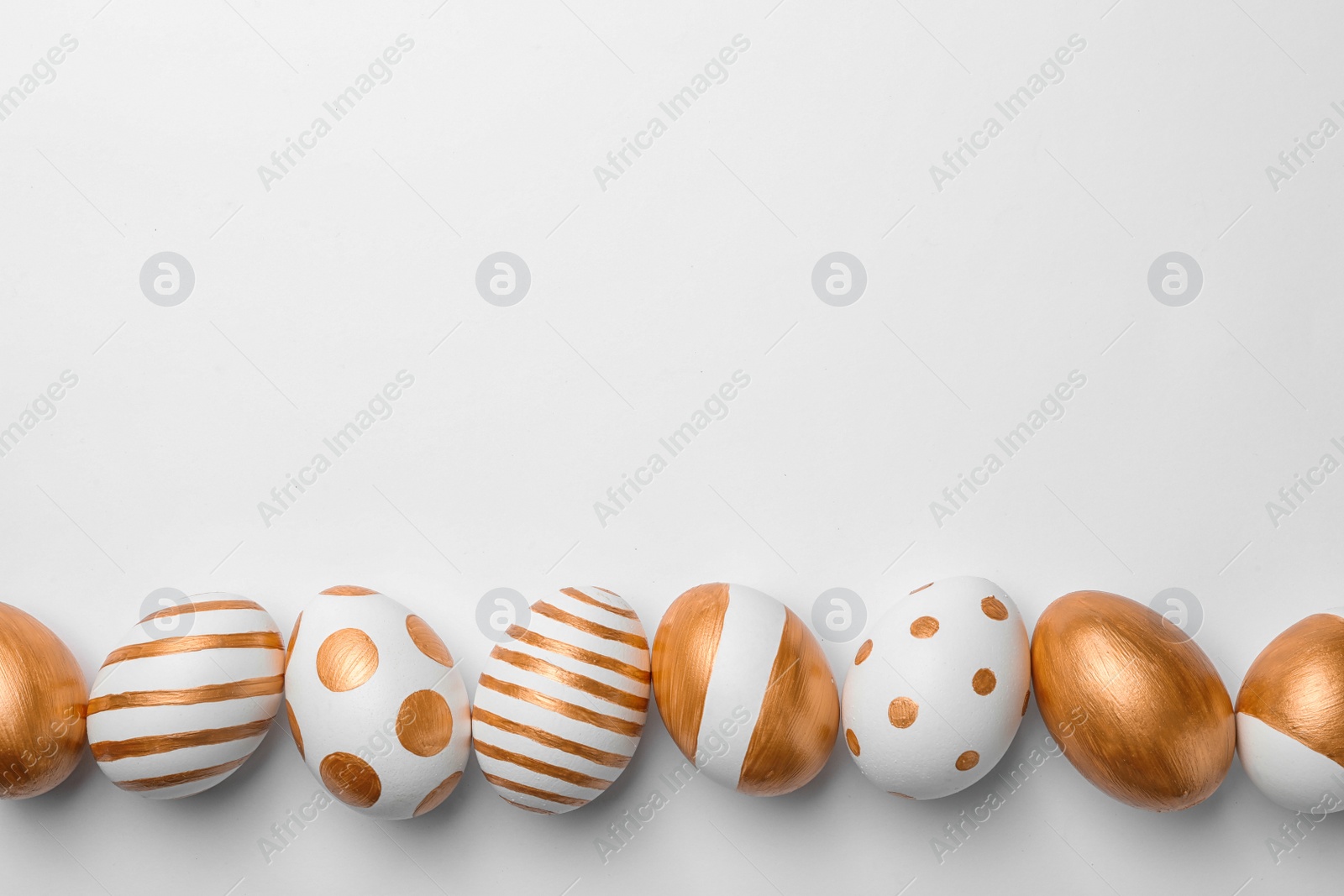 Photo of Set of traditional Easter eggs decorated with golden paint on white background, top view. Space for text