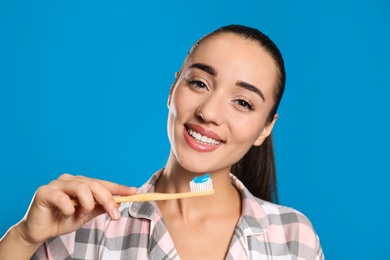 Photo of Woman holding toothbrush with paste on blue background