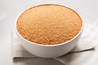 Photo of Brown sugar in bowl on light grey table, closeup