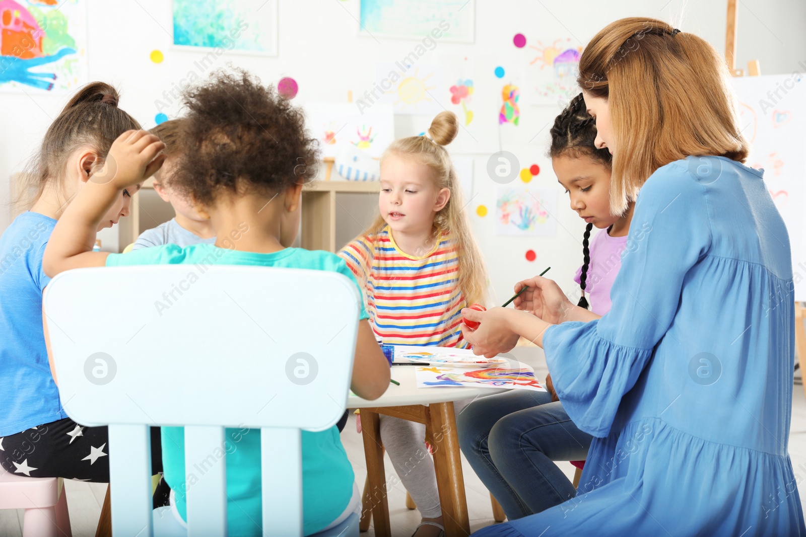 Photo of Children with female teacher at painting lesson indoors