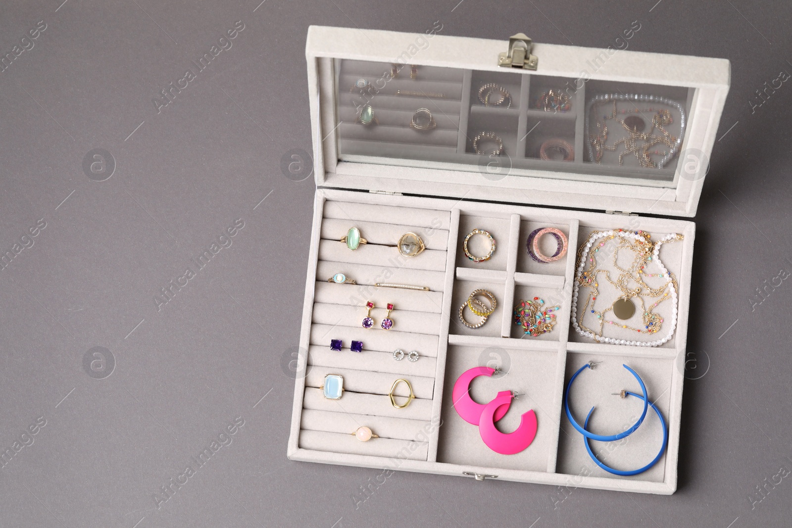 Photo of Jewelry box with many different accessories on gray background, top view. Space for text