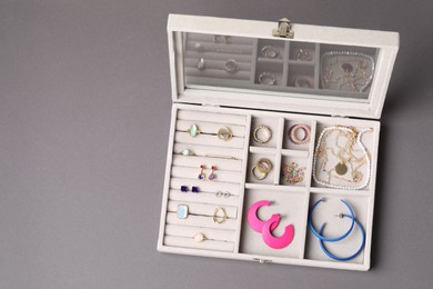 Photo of Jewelry box with many different accessories on gray background, top view. Space for text