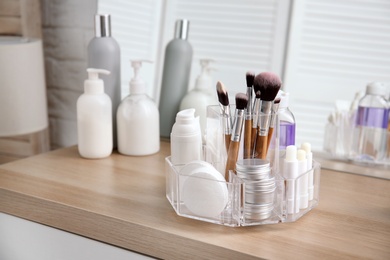 Organizer with cosmetic products on wooden table in bathroom