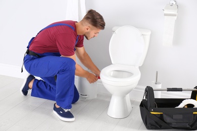 Photo of Young man working with toilet bowl in bathroom