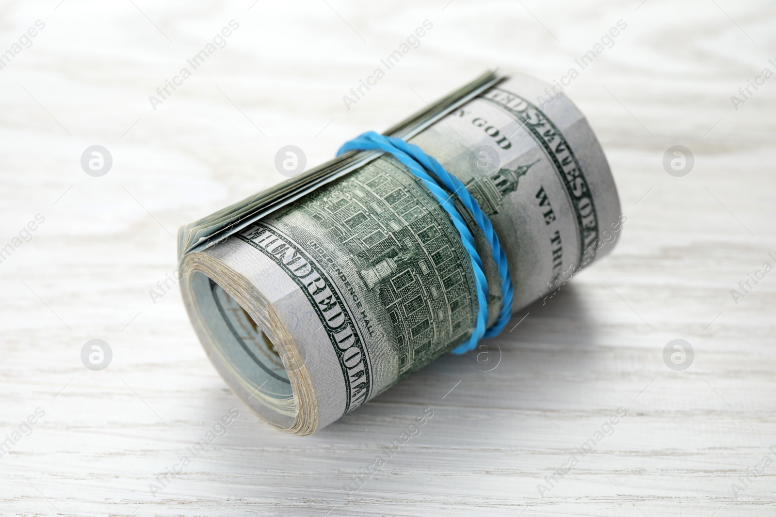 Photo of Rolled dollar banknotes on white wooden table, closeup. American national currency