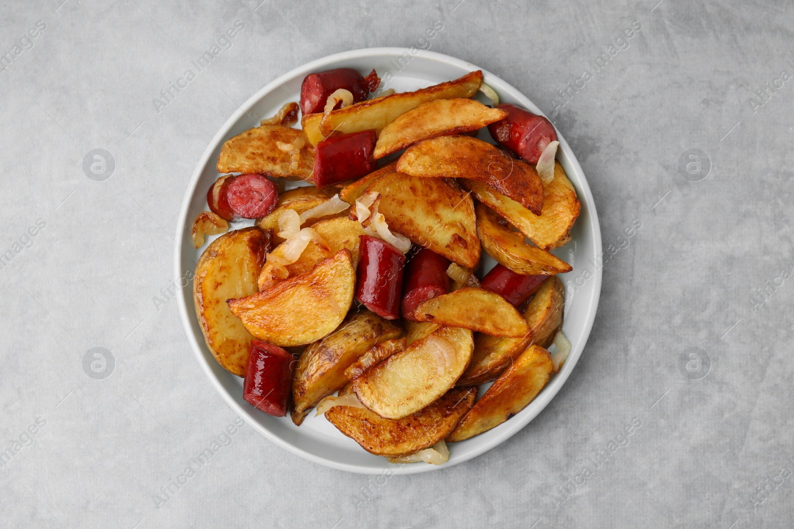 Photo of Delicious baked potato with thin dry smoked sausages and onion on gray table, top view