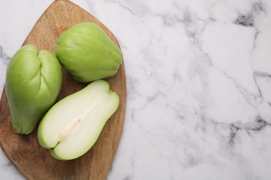 Photo of Fresh green chayote on light marble table, top view. Space for text