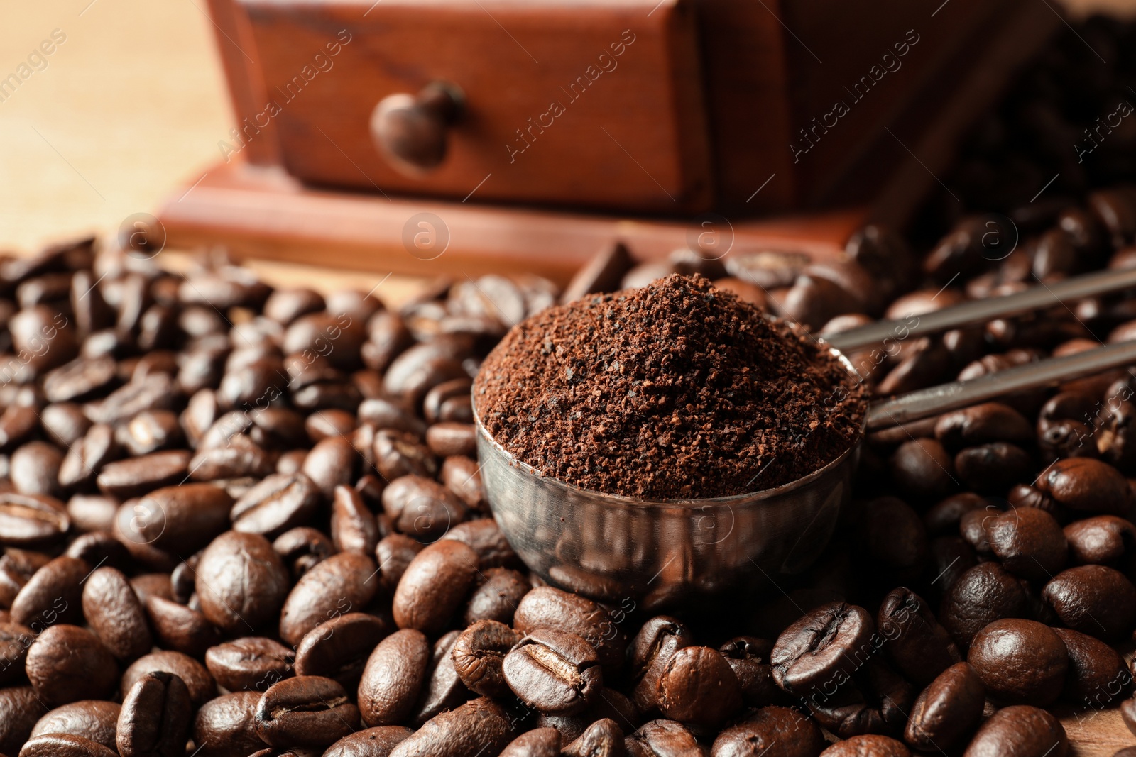 Photo of Spoon with coffee grounds and roasted beans on table, closeup