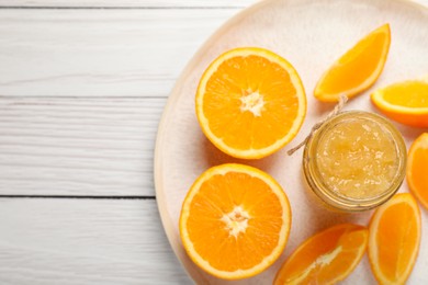 Photo of Jar of delicious orange jam and fresh fruits on white wooden table, top view. Space for text