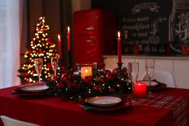 Photo of Table served for festive dinner and Christmas tree in stylish kitchen interior