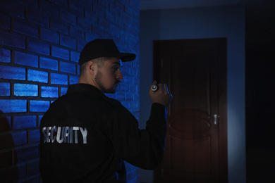 Male security guard with flashlight in dark corridor