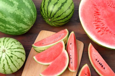 Photo of Different cut and whole ripe watermelons on wooden table, above view