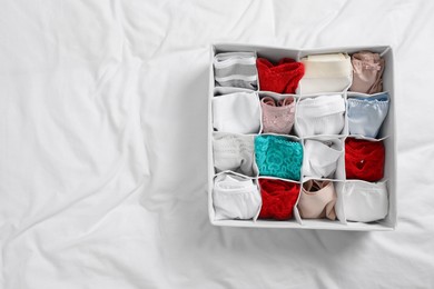 Photo of Organizer with stylish women's underwear on bed, top view. Space for text