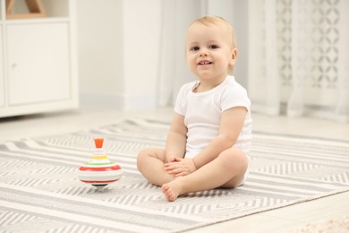 Photo of Children toys. Cute little boy and spinning top on rug at home