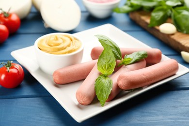 Photo of Fresh raw vegetarian sausages with basil and sauce on blue wooden table