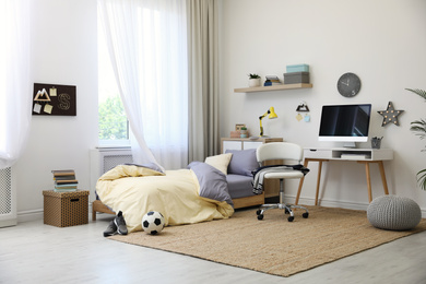 Stylish teenager's room interior with comfortable bed and workplace