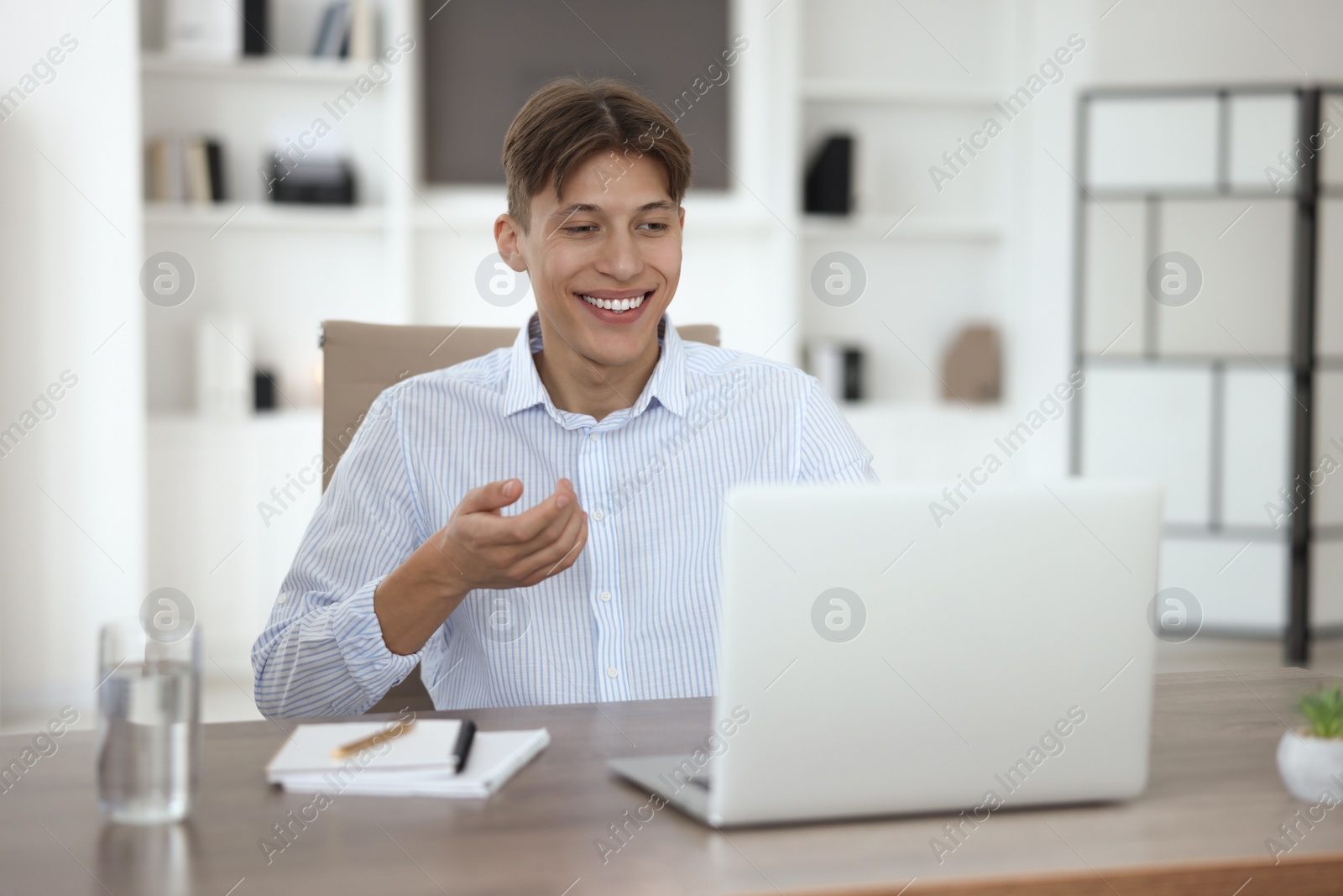 Photo of Man using video chat during webinar at wooden table in office