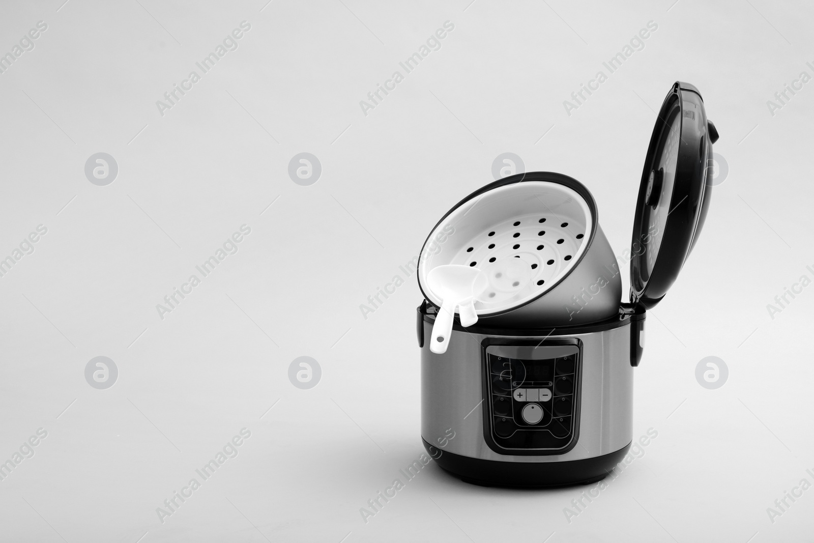 Photo of Modern electric multi cooker, parts and accessories on grey background. Space for text