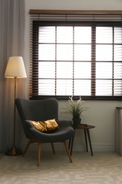 Stylish living room interior with comfortable armchair and window blinds