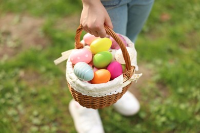 Photo of Easter celebration. Little girl holding basket with painted eggs outdoors, closeup