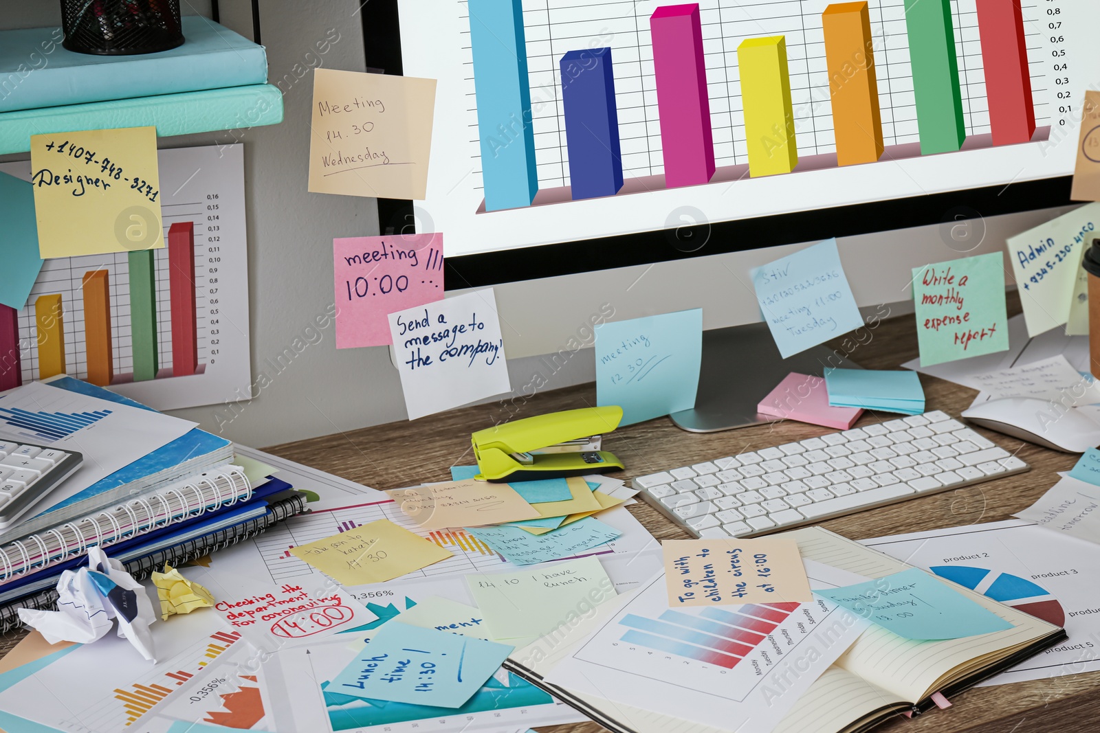 Photo of Computer, notes and office stationery in mess on desk. Overwhelmed with work