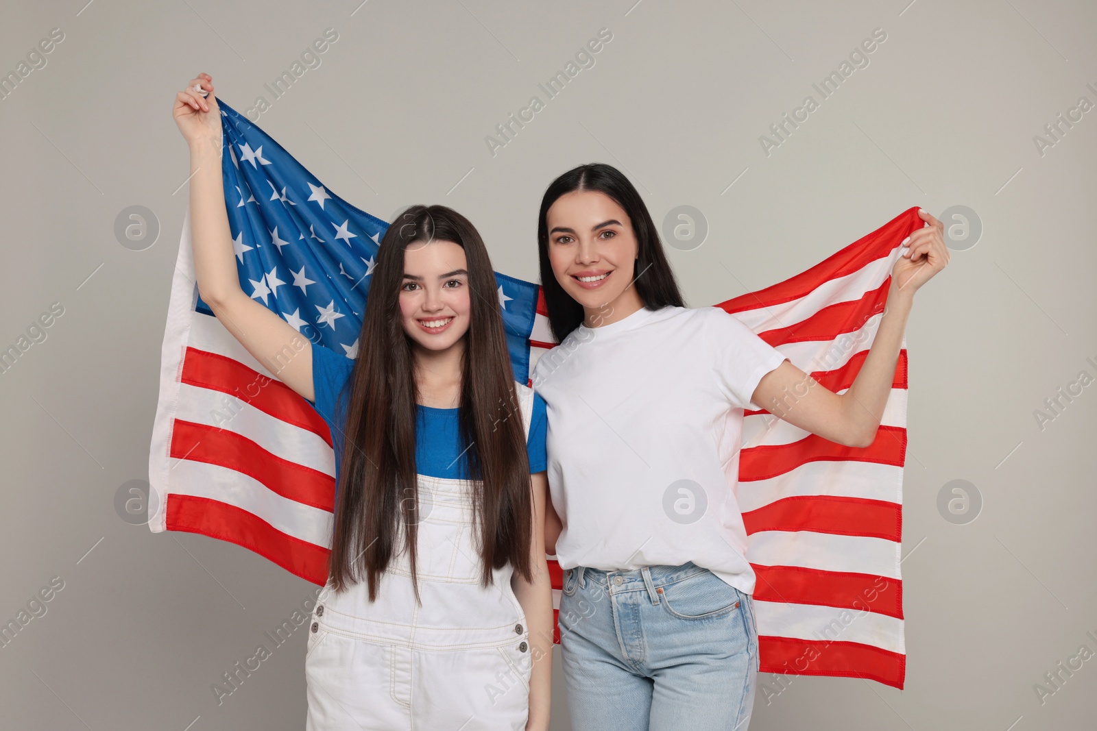 Photo of 4th of July - Independence Day of USA. Happy woman and her daughter with American flag on light grey background