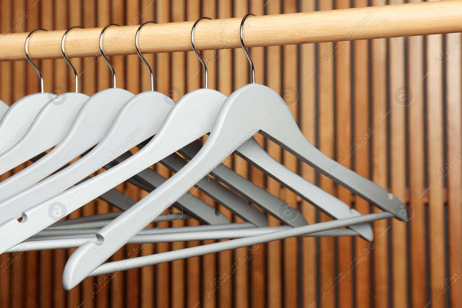 Photo of Empty hangers on rail against wooden background