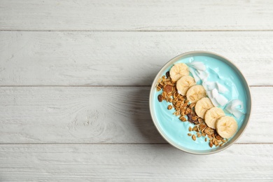 Photo of Bowl of spirulina smoothie on wooden background, top view with space for text