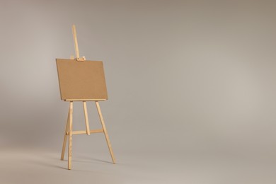 Wooden easel with blank board on grey background. Space for text