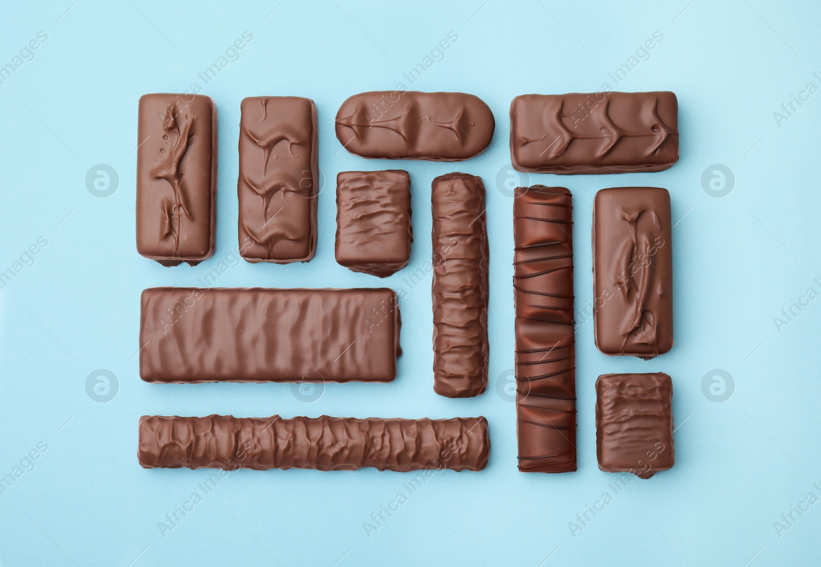 Photo of Different tasty chocolate bars on light blue background, flat lay
