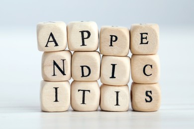 Photo of Word Appendicitis made of wooden cubes with letters on light background