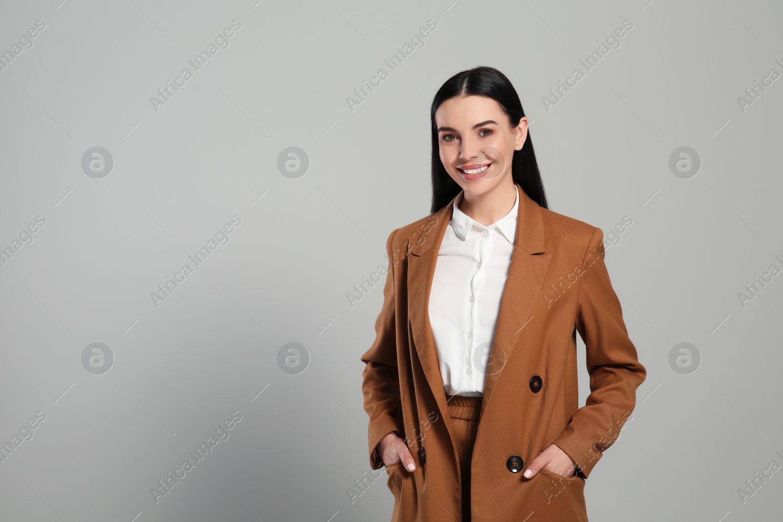 Photo of Beautiful real estate agent in nice suit on grey background, space for text