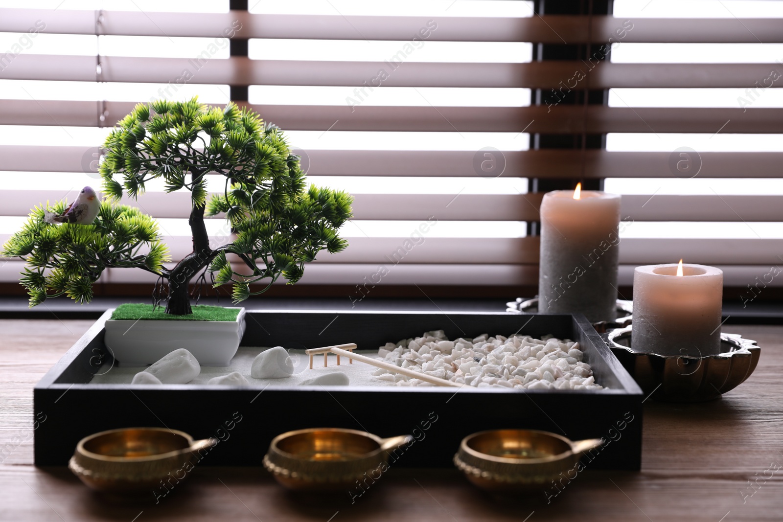 Photo of Beautiful miniature zen garden, candles and oil lamps on wooden table