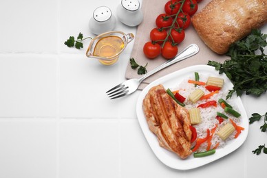 Photo of Grilled chicken breast and rice served with vegetables on white tiled table, flat lay. Space for text