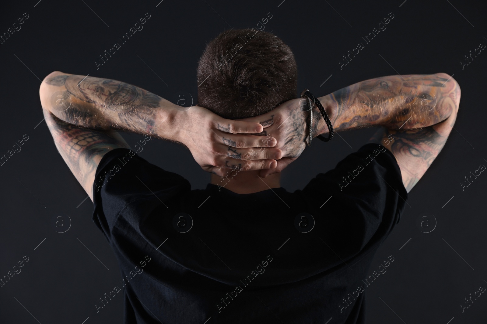 Photo of Handsome hipster man posing on black background, back view