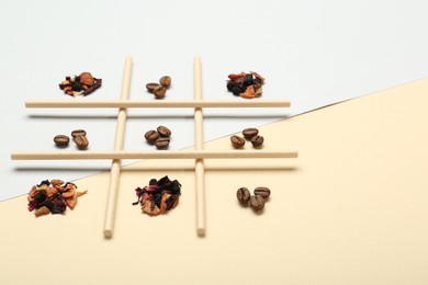 Tic tac toe game made with coffee beans and dry tea leaves on color background